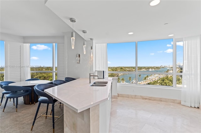 interior space with plenty of natural light, sink, a water view, and pendant lighting