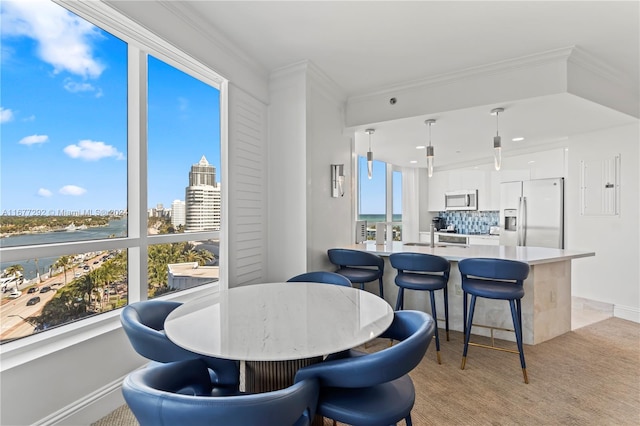 dining space with sink, crown molding, and light carpet