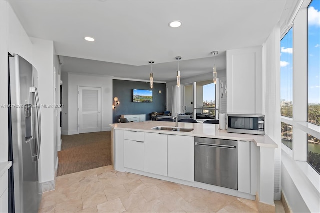 kitchen featuring white cabinets, sink, crown molding, decorative light fixtures, and stainless steel appliances