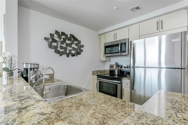 kitchen featuring light stone countertops, appliances with stainless steel finishes, sink, and white cabinets