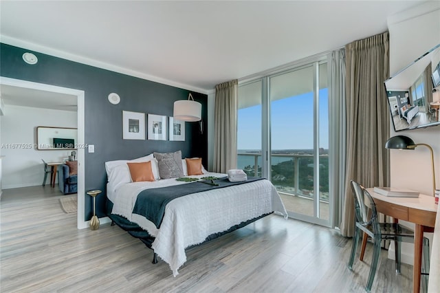 bedroom featuring a water view, access to outside, and light wood-type flooring