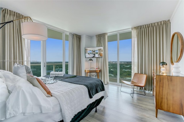 bedroom featuring expansive windows, multiple windows, light wood-type flooring, and access to outside