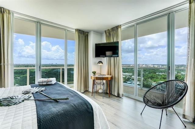 bedroom with floor to ceiling windows, multiple windows, light wood-type flooring, and access to outside