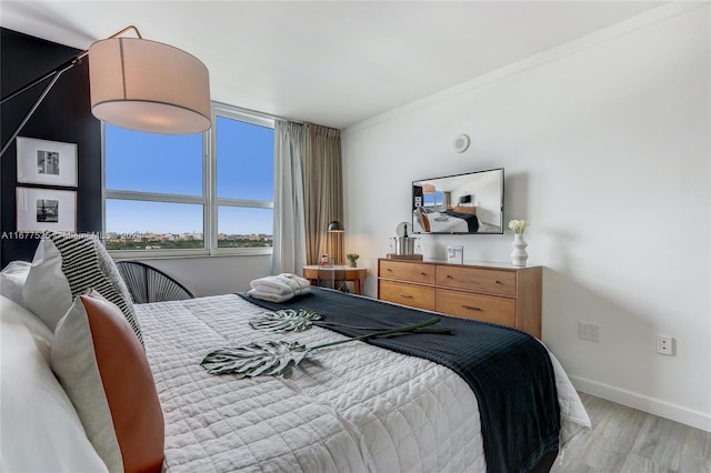 bedroom featuring ornamental molding and light hardwood / wood-style floors