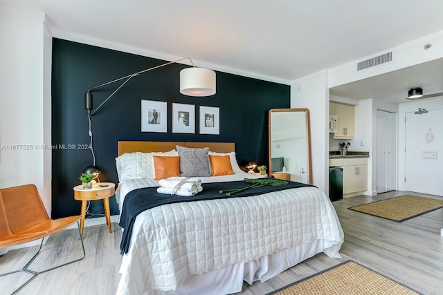 bedroom featuring sink, ensuite bath, and light hardwood / wood-style flooring