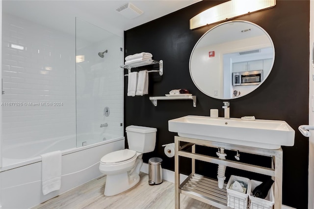 bathroom featuring toilet, hardwood / wood-style flooring, and tub / shower combination