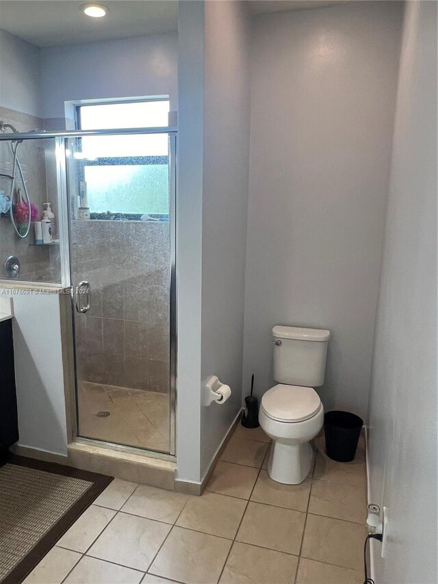 bathroom with tile patterned flooring, toilet, and an enclosed shower