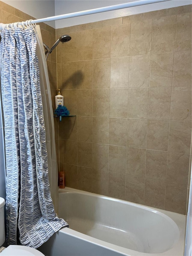 bathroom featuring shower / tub combo and toilet