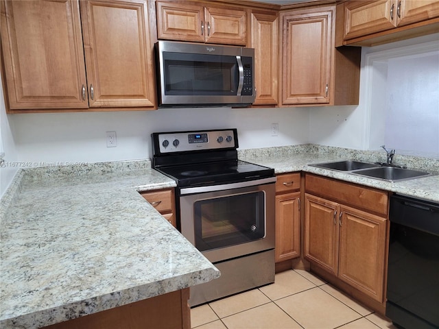 kitchen featuring light stone countertops, light tile patterned flooring, appliances with stainless steel finishes, and sink