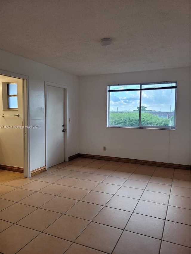 spare room featuring a textured ceiling and light tile patterned floors