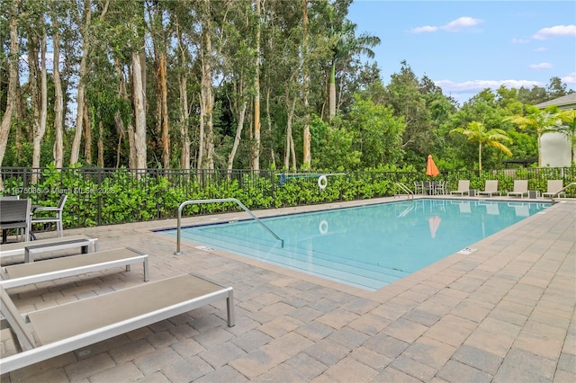 pool with a patio area and fence