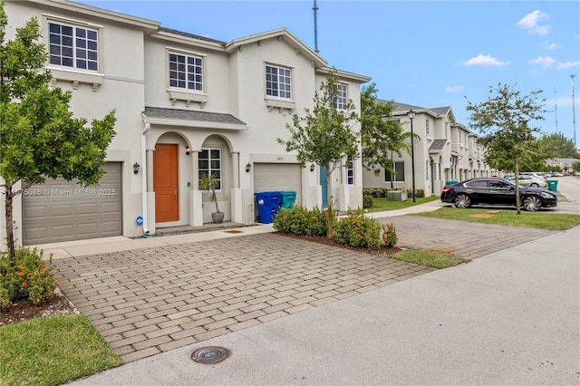 view of front of property featuring stucco siding, decorative driveway, and an attached garage