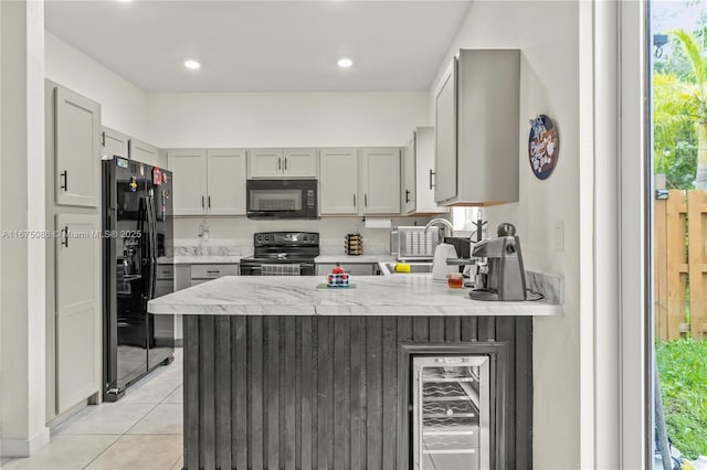 kitchen with black appliances, beverage cooler, a sink, a peninsula, and light tile patterned floors