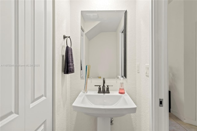 bathroom with tile patterned floors, a textured wall, and a sink