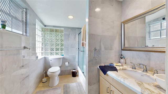 full bathroom featuring toilet, tile patterned flooring, tile walls, vanity, and enclosed tub / shower combo