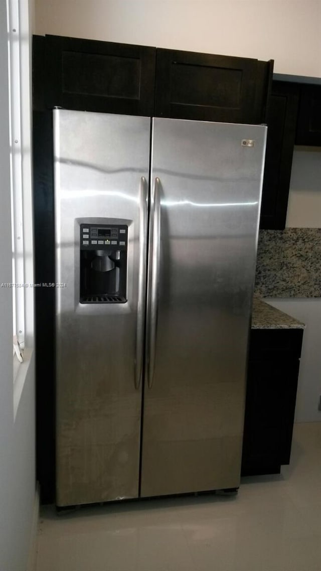 kitchen with stainless steel fridge with ice dispenser and light stone counters