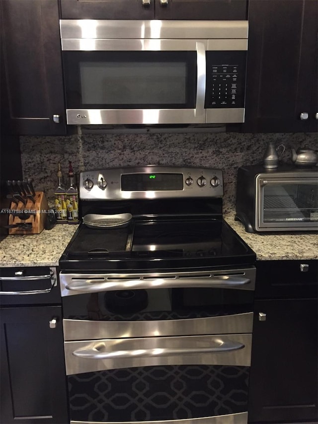 kitchen with light stone counters, stainless steel appliances, and backsplash