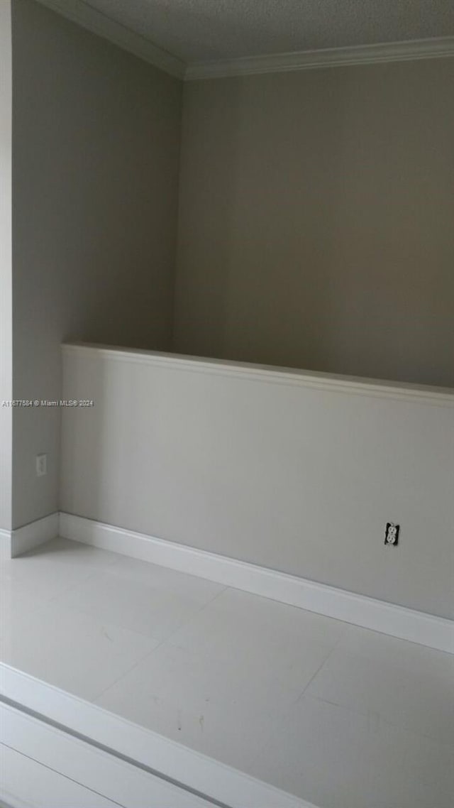 unfurnished room featuring crown molding and a textured ceiling