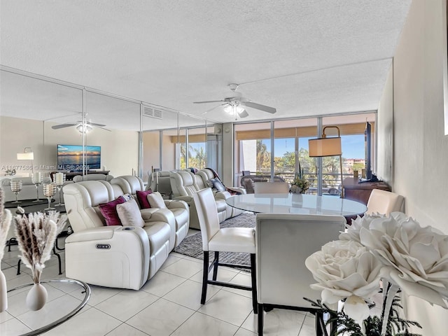 living room featuring ceiling fan, a textured ceiling, light tile patterned floors, and floor to ceiling windows