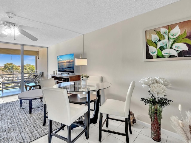 tiled dining room featuring expansive windows, a textured ceiling, and ceiling fan