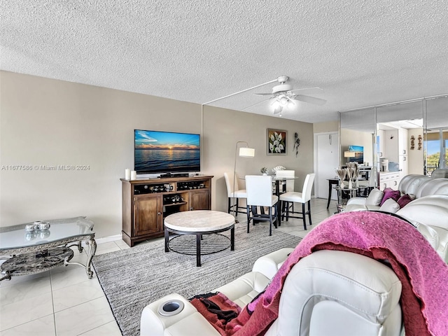 living room with a textured ceiling, light tile patterned flooring, and ceiling fan