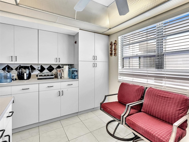 kitchen featuring ceiling fan and white cabinets