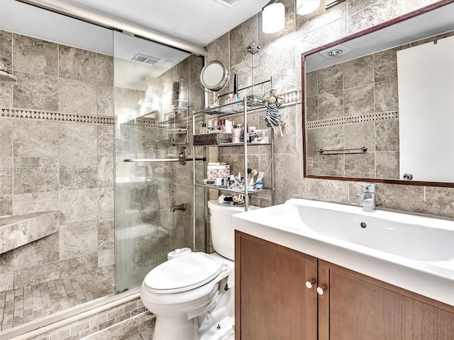 bathroom featuring vanity, toilet, walk in shower, and tile walls