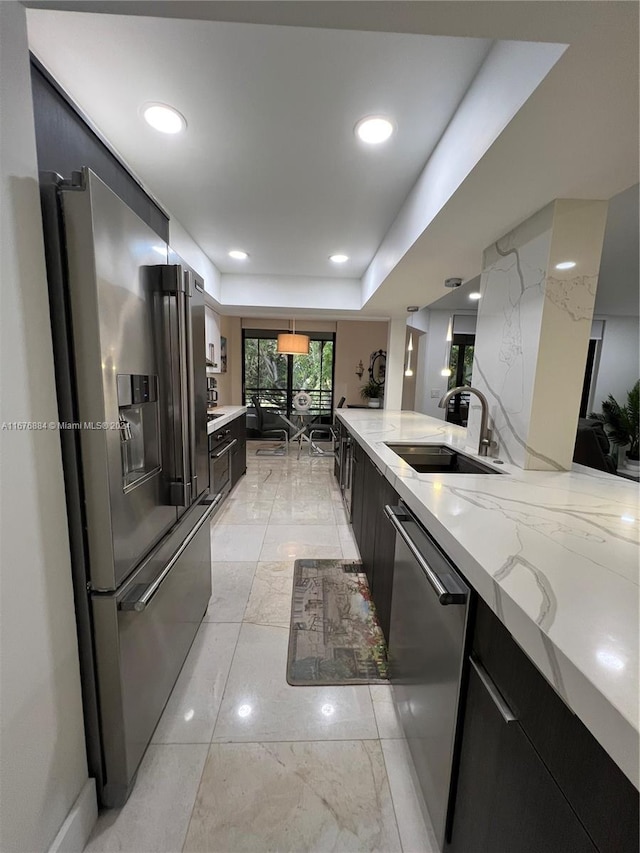 kitchen with light stone countertops, sink, a raised ceiling, kitchen peninsula, and stainless steel appliances