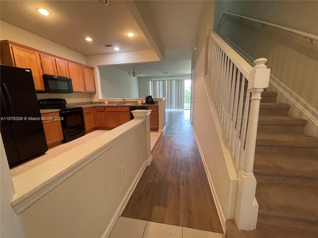kitchen featuring recessed lighting, a sink, baseboards, black appliances, and a peninsula