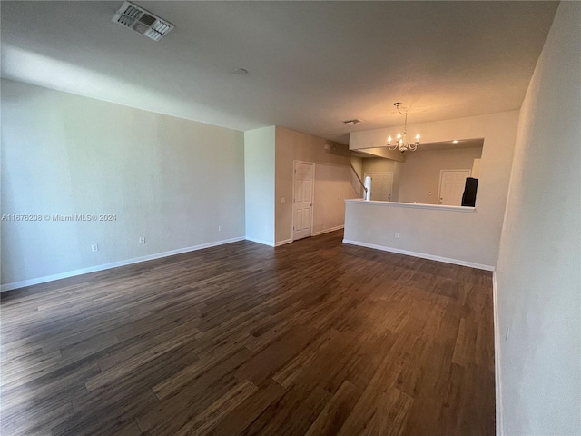 unfurnished living room featuring an inviting chandelier and dark hardwood / wood-style flooring