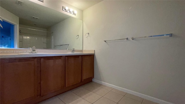 bathroom featuring tile patterned floors, baseboards, a sink, and double vanity