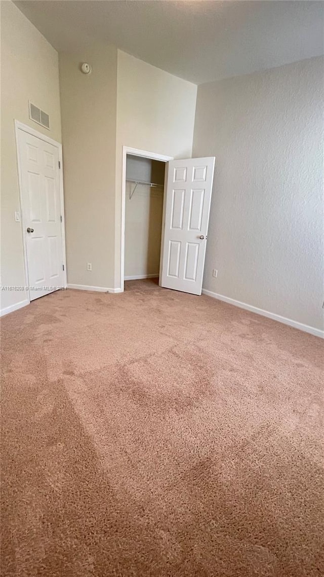 unfurnished bedroom featuring vaulted ceiling, visible vents, carpet flooring, and baseboards