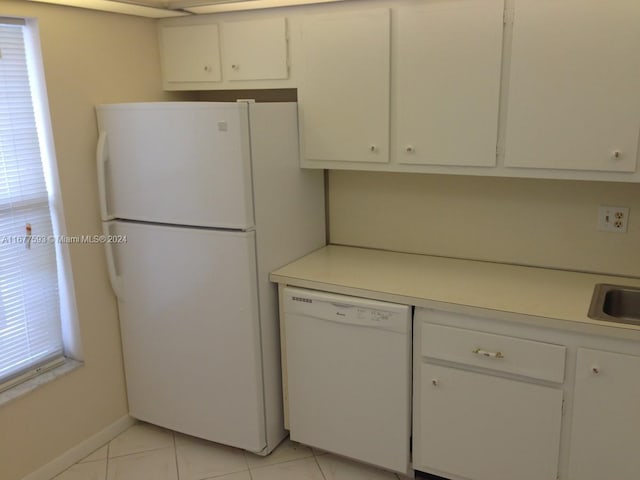 kitchen featuring white appliances, light tile patterned floors, and white cabinets