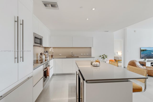 88 SW 7th St Unit 1710, Miami, FL 33130 - kitchen with appliances with stainless steel finishes, modern cabinets, a center island, white cabinets, and a sink