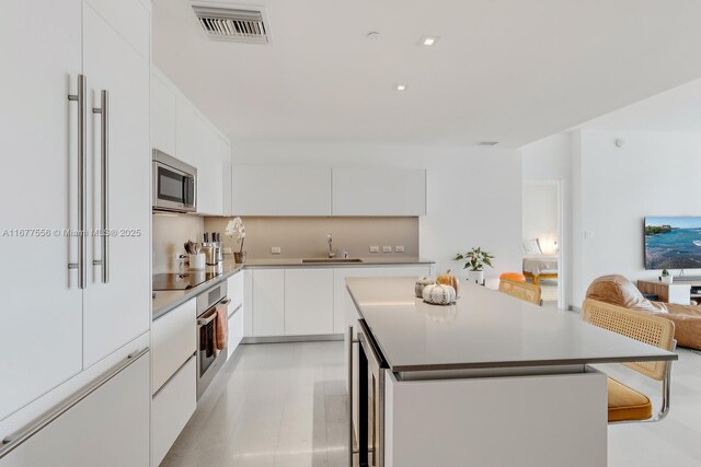 88 SW 7th St Unit 1710, Miami, FL 33130 - kitchen featuring stainless steel appliances, modern cabinets, a center island, a sink, and white cabinets