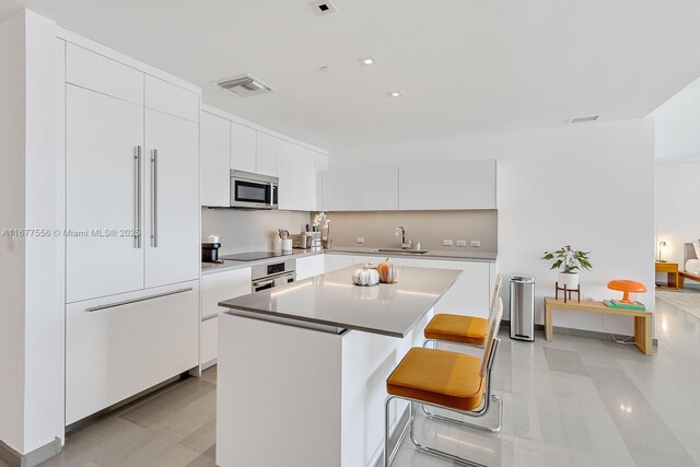 88 SW 7th St Unit 1710, Miami, FL 33130 - kitchen with stainless steel appliances, a sink, a center island, white cabinets, and modern cabinets