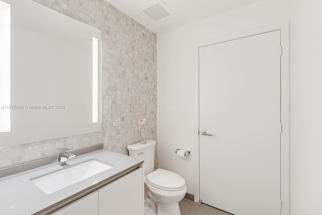 bathroom featuring tile patterned floors, vanity, toilet, and tile walls