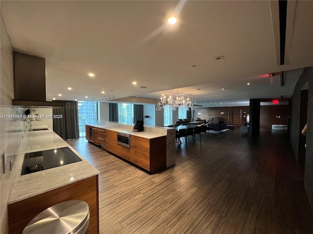 88 SW 7th St Unit 1710, Miami, FL 33130 - kitchen with black electric stovetop, wood finished floors, a chandelier, brown cabinetry, and recessed lighting