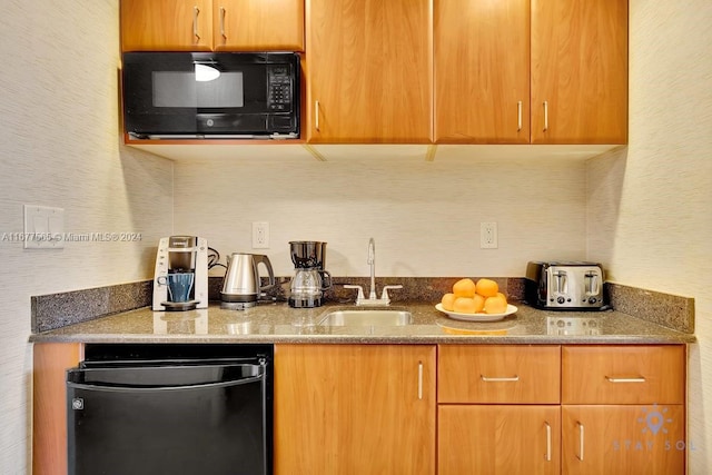 kitchen with sink, stone countertops, and black appliances