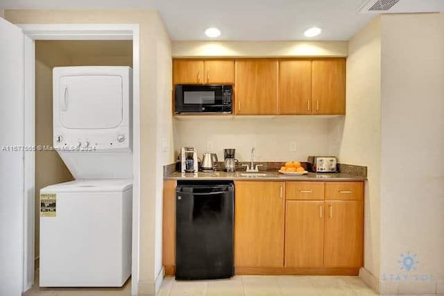 kitchen with stacked washing maching and dryer, sink, light tile patterned floors, and black appliances