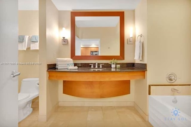 bathroom featuring tile patterned floors, vanity, a tub to relax in, and toilet