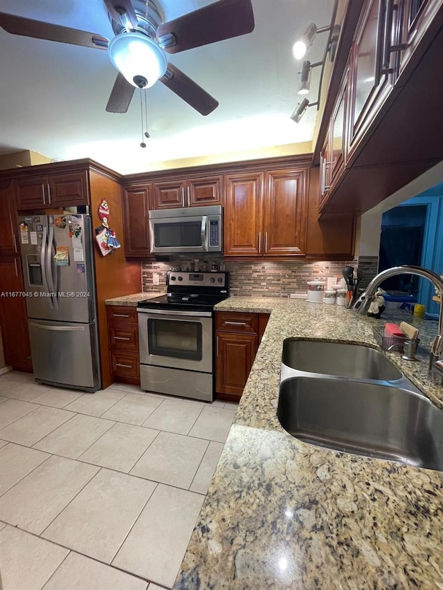 kitchen with decorative backsplash, stainless steel appliances, sink, light tile patterned floors, and light stone counters