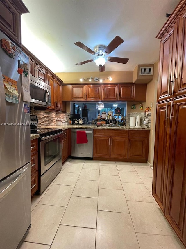 kitchen with decorative backsplash, stone countertops, sink, light tile patterned flooring, and appliances with stainless steel finishes