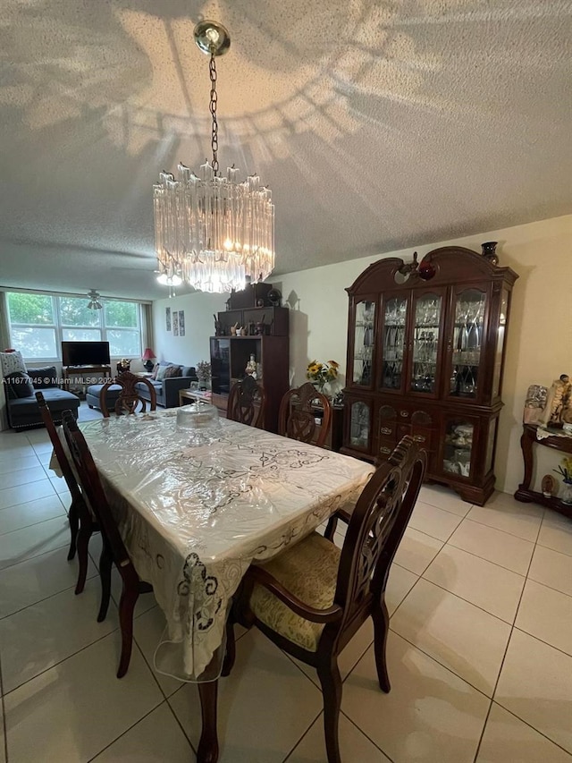 tiled dining room featuring a textured ceiling and a chandelier