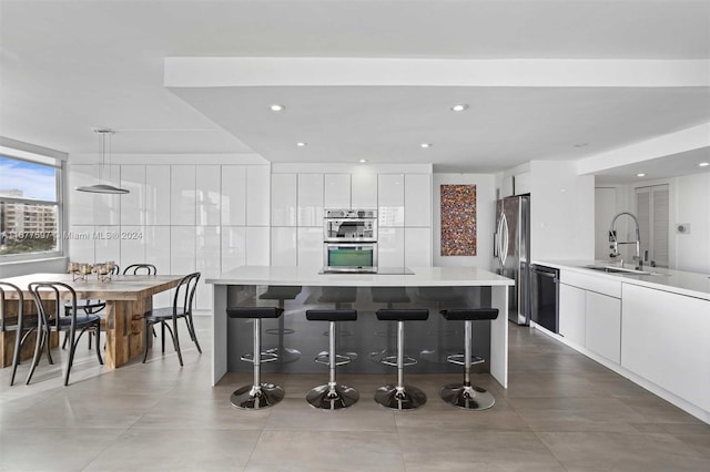 kitchen featuring decorative light fixtures, stainless steel appliances, white cabinetry, and sink