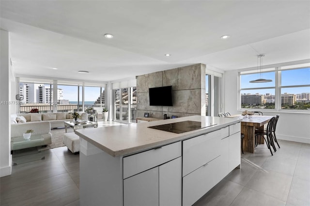 kitchen featuring white cabinets, black electric stovetop, a kitchen island, and pendant lighting