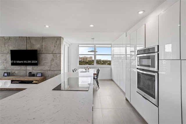 kitchen featuring black electric stovetop, decorative light fixtures, light stone counters, and white cabinetry