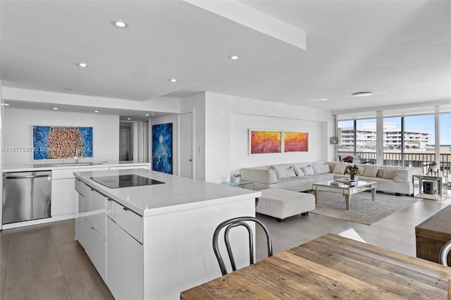 kitchen featuring black electric stovetop, stainless steel dishwasher, sink, white cabinetry, and a kitchen island