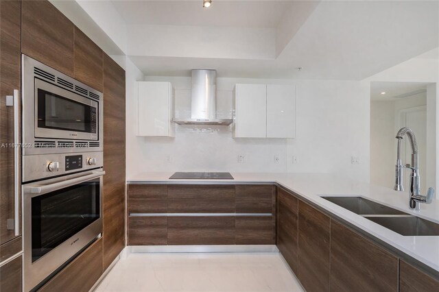 kitchen with sink, white cabinetry, wall chimney range hood, and stainless steel appliances