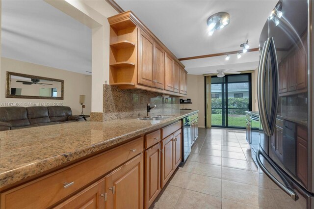 kitchen featuring black dishwasher, decorative backsplash, sink, stainless steel fridge, and light stone counters